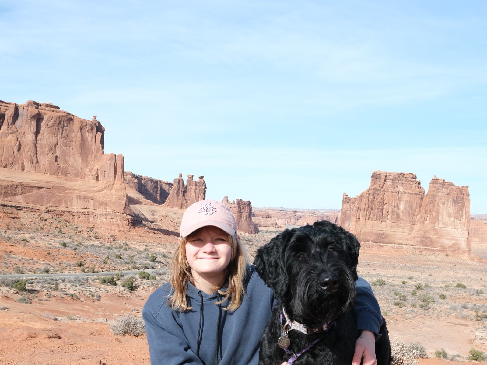 Bee sitting on red rock with Delilah, her black giant schnauzer